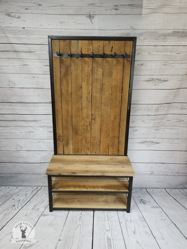 Rustic reclaimed barnwood hall tree with full barnwood back, row of repurposed railroad spike coat hooks, two shoe shelves, bench seat and welded steel frame with an antiqued blackened finish.