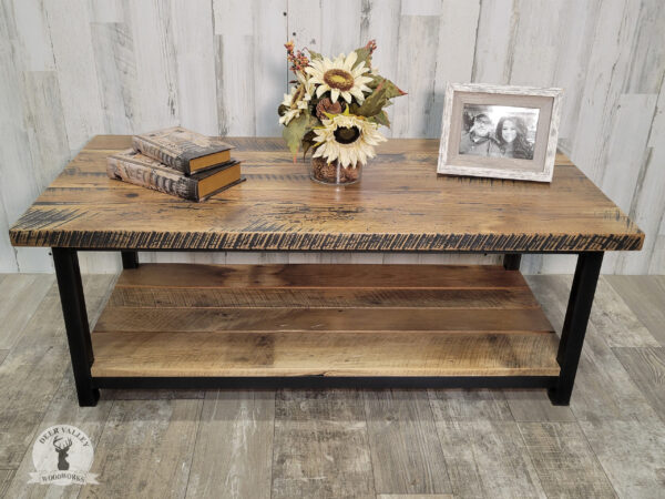 Rustic coffee table with rectangle barnwood top and a lower shelf on at blackened welded steel frame.