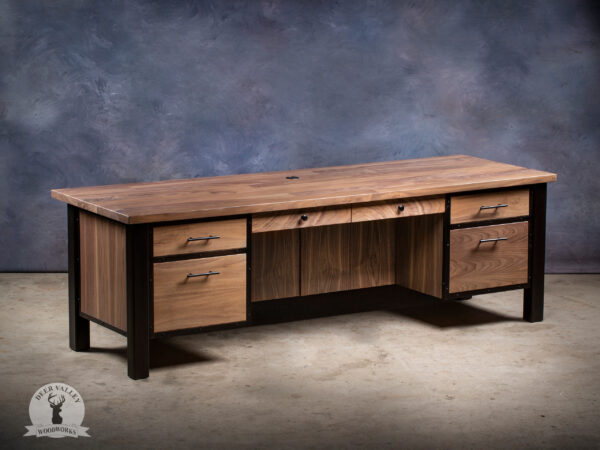 Modern black walnut executive desk with a massive desktop, two regular drawers, two file drawers, large center drawer, modesty panels, and industrial welded steel legs and framework.