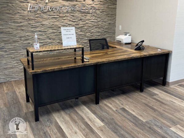 Industrial corner reception desk with a large sized barnwood top atop solar black welded steel legs connected by solid steel panels.