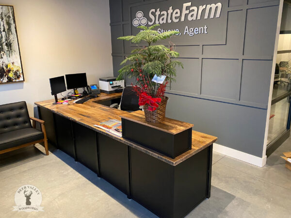 Industrial style reception desk with a oversized barnwood top atop solar black welded steel legs connected by solid steel panels.