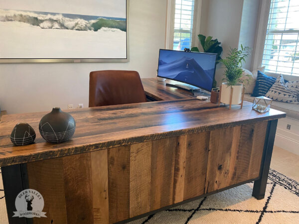 Rustic barnwood corner desk with a large desktop, modesty panels, lap drawer, bank of three drawers and storage cabinet with an antique blackened welded steel frame.