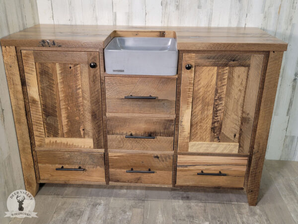 Farmhouse reclaimed barnwood vanity with concrete sink basin set in a barnwood top with three drawers under the sink, barnwood door on each end of the vanity with a drawer underneath.