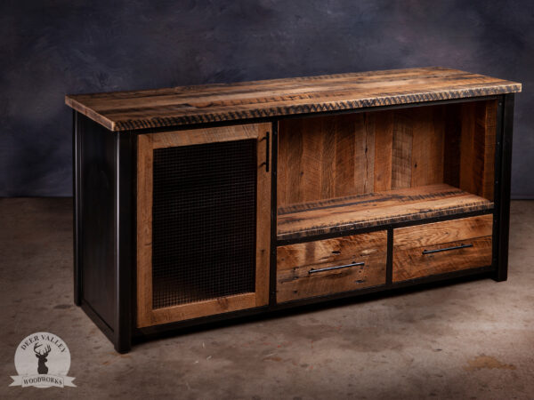 Rustic reclaimed barnwood coffee bar with large barnwood top, antique blackened welded steel frame, large cabinet with steel mesh door, a large open barnwood shelf illuminated with LED strip lights with two large drawers underneath.