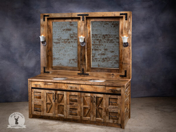 Rustic barnwood vanity with two oversized, framed mirrors across the full width of the vanity with sconces and shallow shelves and the vanity has a large countertop with double sinks, three bank of triple drawers, two double door cabinets, and on the front is blackened metal strap on the face and outside corner brackets on the countertop.