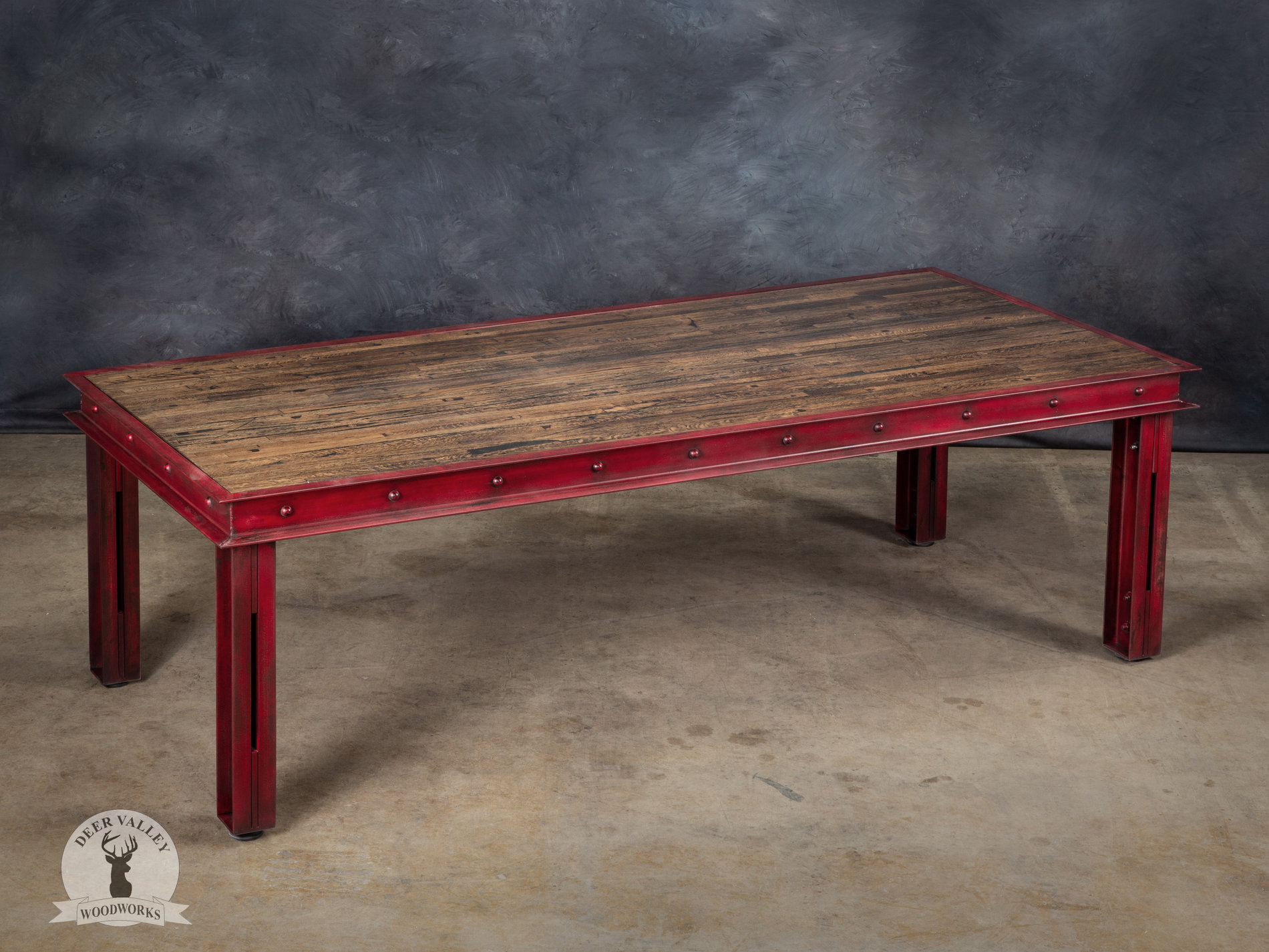 Industrial modern table with a huge, reclaimed wood top rapped in a red welded riveted frame supported by red structural steel channel legs.