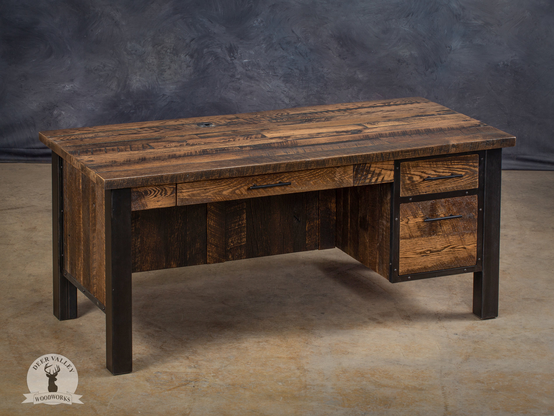 Authentic barnwood executive desk with a Jacobean stained finish, a large desktop, pencil drawer, two drawers, modesty panels, and blackened welded steel frame.