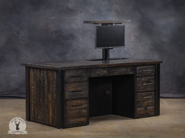 Ebonized barnwood industrial executive desk with electric monitor lift, large desktop, modesty panels, pencil drawer, dual bank of three drawers, and welded steel frame.