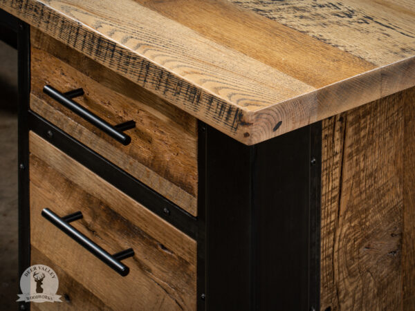Closeup of the corner of a reclaimed wood corner desk showing barnwood drawer fronts and black drawer pulls.