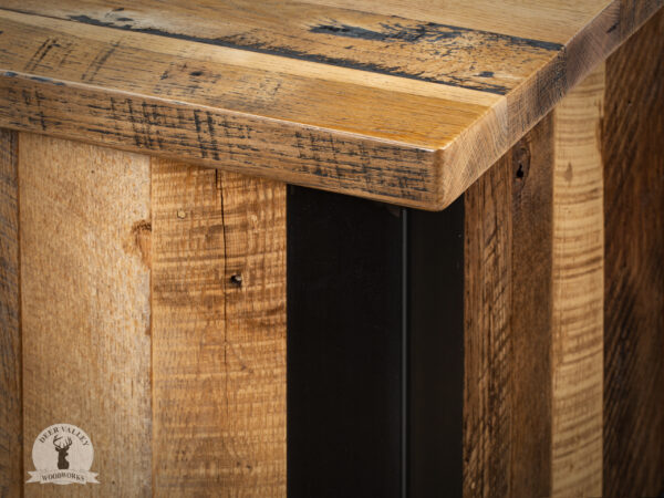 Closeup of the corner of a rustic barnwood corner desk with antique blackened steel frame.